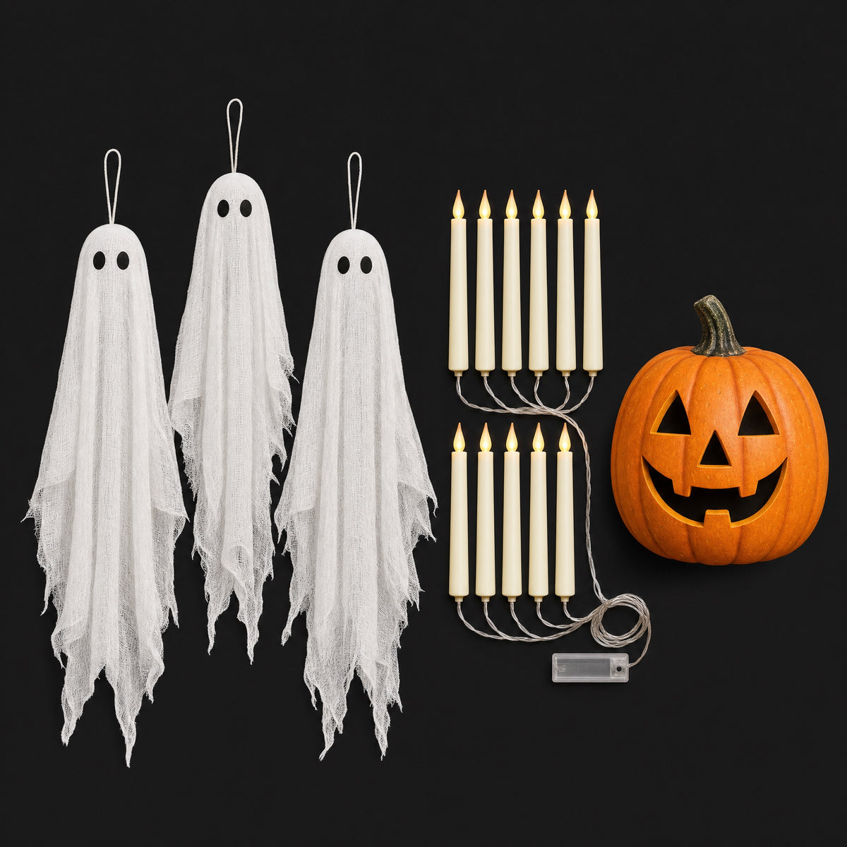 The Haunting Trio: three hanging gauze ghosts, a garland of flameless flickering candles and a lit smiling pumpkin on a black background