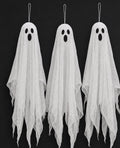 Three hanging gauze ghosts with dark oval eyes against a black background