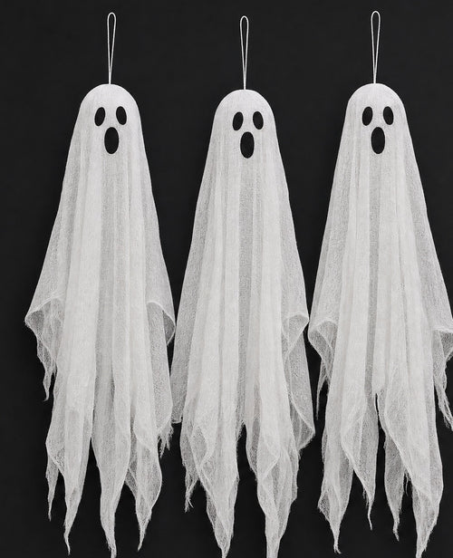 Three hanging gauze ghosts with dark oval eyes against a black background