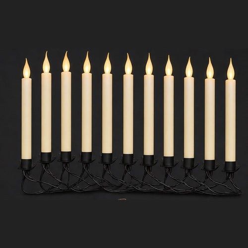 Row of ivory flameless taper candles with warm flickering LED flames on a black wire garland